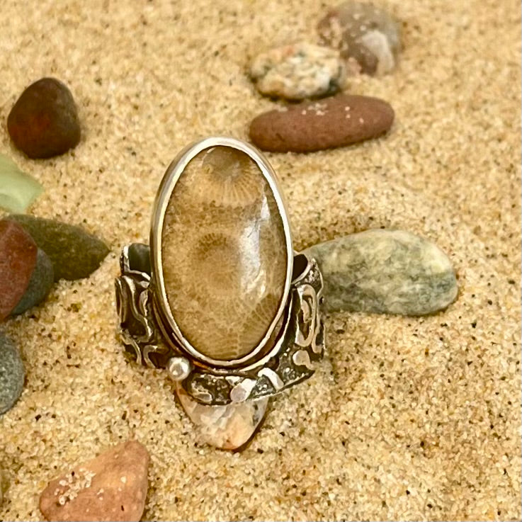 Sterling silver and Petoskey Stone Ring. Very unique sterling silver band embellished with fused abstract sterling silver designs. Band accommodates an off-set oval Petoskey Stone cabochon. While sized at a 7.5 ring size, the wide band requires sizing down and fits more comfortably as a size 7.