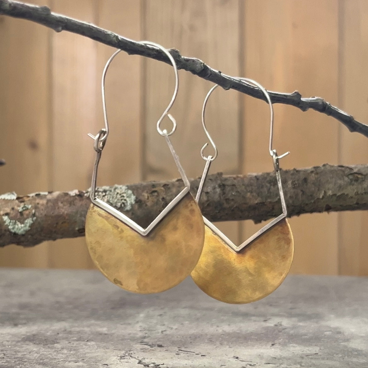 Hammered brass almost half circles with v-shaped cut trimmed in silver with an upside-down pentagon. Sterling silver earwire completes this side dangling earring. Very clean and attractive design.