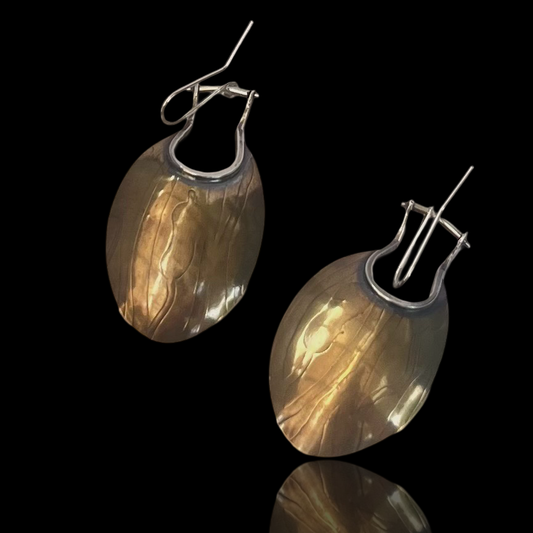 Brass  circles with soft patina and roller-printed cattails are shaped into a spoon shape by compressing a u-shaped cut out at the top.  Trimmed in sterling silver these earrings provide a bold clean look. 