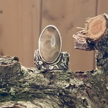 Sterling silver and Petoskey Stone Ring.  Very unique sterling silver band  embellished with fused abstract sterling silver designs.  Band accommodates an off-set oval Petoskey Stone cabochon. While sized at a 7.5 ring size, the wide band requires sizing down and fits more comfortably as a size 7.