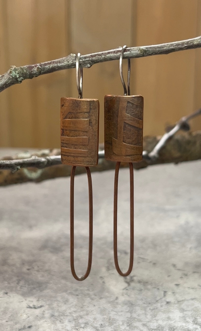 Roller printed copper, with rich patina, rectangle dangle earring with fixed earwire.  A copper silver paperclip chain links hangs off the bottom of the earring body.
